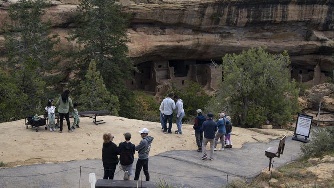 MANCOS, COLORADO - OCTOBER 4: Visitors view the cliff dwellings next to trail closed signs inside Mesa Verde National Park during the government shutdown on October 4, 2025 in Mancos, Colorado. National Park Trails and open-air sites remain open, while most staffed facilities closed due to the government shut down early last Wednesday after Congress failed to reach a funding deal.