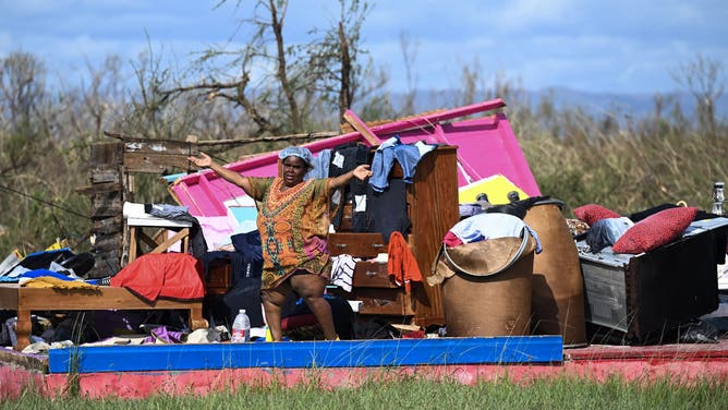 TOPSHOT - Nicola Gowdie who lost her entire home, stands on October 29, 2025 where only the foundation of the building remains following the passage the previous day of Hurricane Melissa, in the Fullerswood community, St. Elizabeth, Jamaica. Hurricane Melissa bore down on the Bahamas October 29 after cutting a path of destruction through the Caribbean, leaving 30 people dead or missing in Haiti and parts of Jamaica and Cuba in ruins.