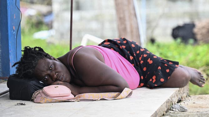 A woman lies along a plaza after her home was destroyed by Hurricane Melissa in Lacovia, St Elizabeth, Jamaica, on October 31, 2025. At least 19 people in Jamaica have died as a result of Hurricane Melissa which devastated the island nation when it roared ashore this week, a government minister told news outlets late October 31. (Photo by Ricardo Makyn / AFP) (Photo by RICARDO MAKYN/AFP via Getty Images)