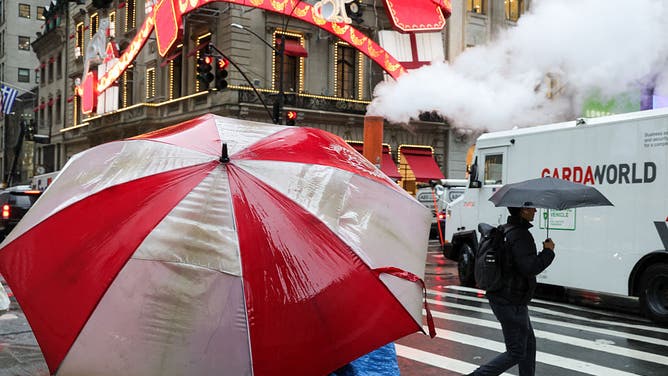 Pedestrians carry umbrellas as they walk in the rain in Midtown Manhattan in New York City on December 2, 2025.