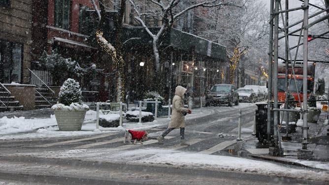 A person walks on a snow-covered ground in the Brooklyn borough of New York City on December 14, 2025.