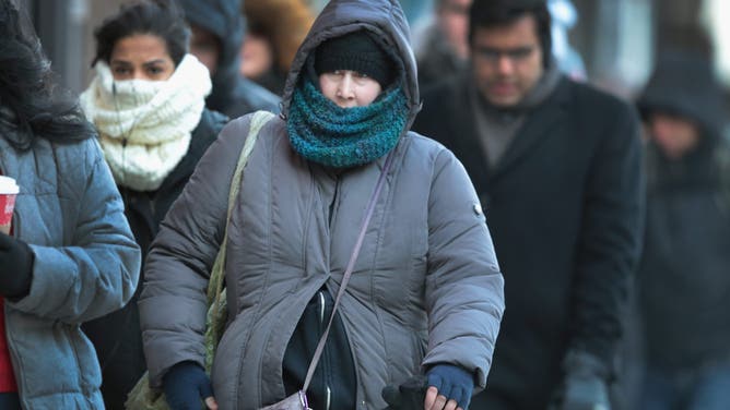 CHICAGO, IL - DECEMBER 15: Commuters, bundled for warmth, walk toward an L station on December 15, 2016 in Chicago, Illinois.