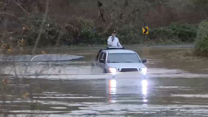 Pickup truck drives through flooded road in King County. Emergency officials warn people not to drive through flooded roads.