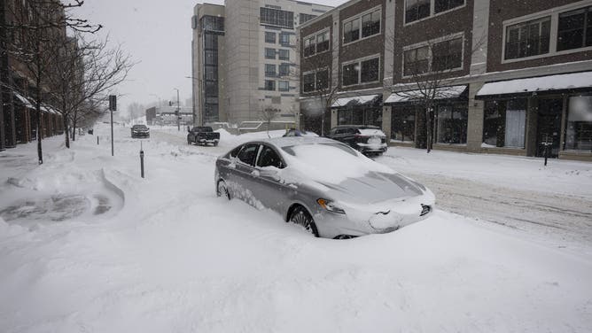 TOPSHOT - A car is buried in snow during a blizzard in the East Village neighborhood of Des Moines, Iowa, on January 12, 2024. Weather advisories were issued on January 12 as a powerful storm moved over the Plains and Midwest regions. The National Weather Service reports highs will not rise above 0F (-18C) degrees across Montana and North Dakota and high temperatures in the Central Plains states will reach around the 10s (-12F).