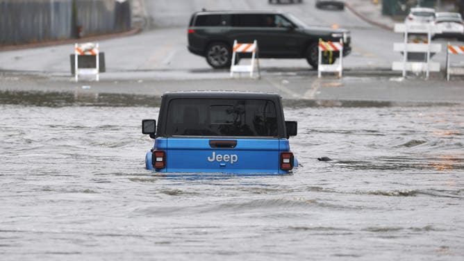 San Diego, CA - January 1: An adult and a child were rescued from a Jeep on Fashion Valley Road by the San Diego Lifeguard River Rescue Team after San Diego River overflowed and flooded areas in Mission Valley during a storm on January 1, 2026 in San Diego, CA.