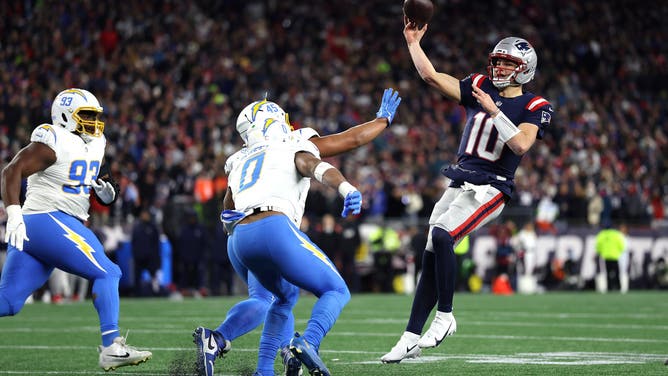 FOXBOROUGH, MASSACHUSETTS - JANUARY 11: Drake Maye #10 of the New England Patriots passes the ball under pressure from Otito Ogbonnia #93, Tuli Tuipulotu #45 and Daiyan Henley #0 of the Los Angeles Chargers during the first quarter of the AFC Wild Card Playoff game at Gillette Stadium on January 11, 2026 in Foxborough, Massachusetts.