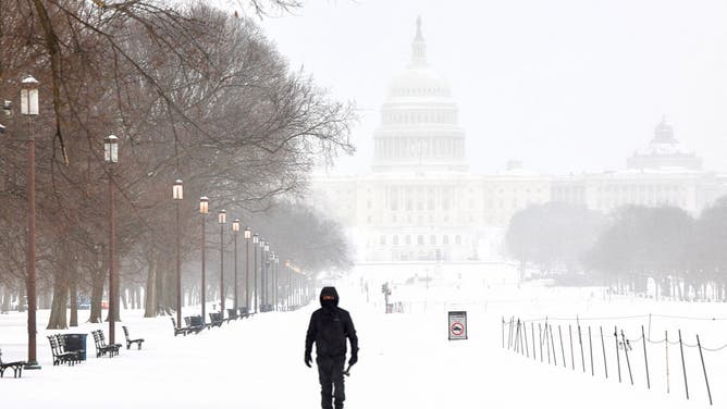 WASHINGTON- A man walks along the National Mall as snow falls in Washington, DC, on January 25, 2026.