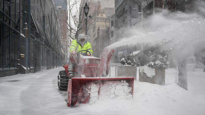 A worker clears snow off a sidewalk in Philadelphia, Pennsylvania, on January 25, 2026.