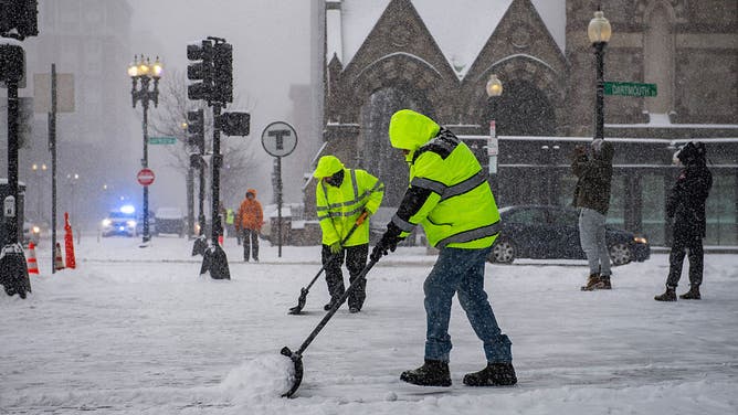 Workers clear snow in Copley Square during a snowstorm in Boston, Massachusetts, on January 25, 2026. 