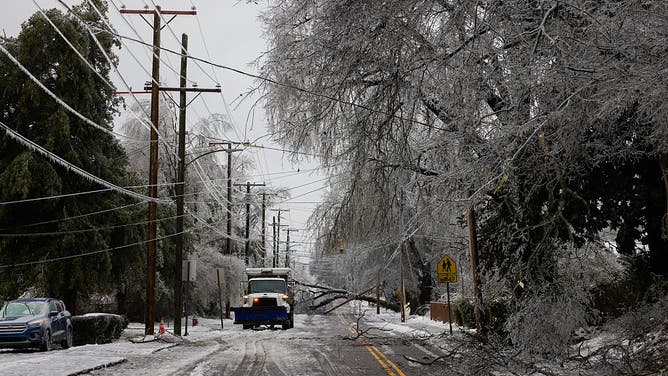 A snow plow near a fallen tree and electrical pole during a winter storm in east Nashville, Tennessee, US, on Sunday, Jan. 25, 2026.