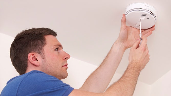man installing smoke alarm