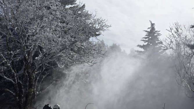 Snow swirls in the air as a UH-60 Black Hawk helicopter from the National Guard hovers over a rescue site for an injured hiker.