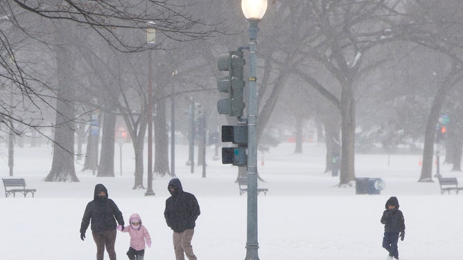 A family walks in the snow near the National Mall in Washington, DC, on January 25, 2026.