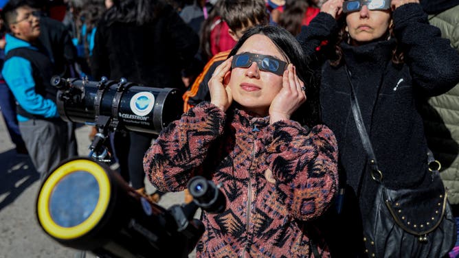 02 October 2024, Chile, Coyhaique: People look up at the sky before the annular solar eclipse. Photo