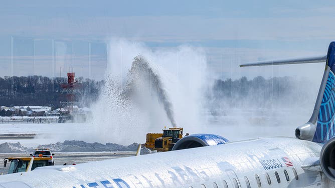 A United Airlines plane as snow is removed from the tarmac at Ronald Reagan Washington National Airport (DCA) in Arlington, Virginia, US, on Monday, Jan. 26, 2026.