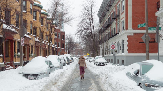 A pedestrian passes snow-covered vehicles following a winter storm in Boston, Massachusetts, US, on Monday, Jan. 26, 2026.
