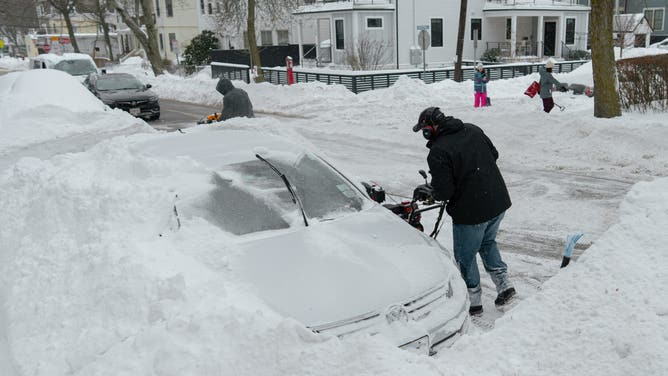 A resident clears snow surrounding a vehicle in Somerville, Massachusetts, US, on Monday, Jan. 26, 2026.
