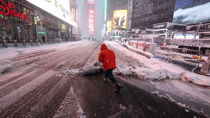 A person clears a snow covered street during a winter storm in the Manhattan borough of New York City on February 23, 2026.