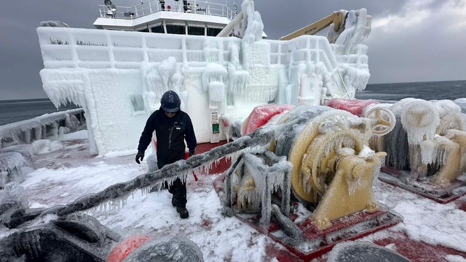 Crews on a Canadian Coast Guard ship work to break up large amounts of ice buildup on the boat.