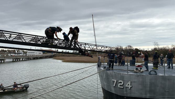 First responders lead people over a ladder after becoming stranded on the USS Laffey in South Carolina.