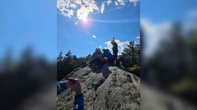 First responders prepare an injured hiker to be hoisted to safety by a helicopter in North Carolina.