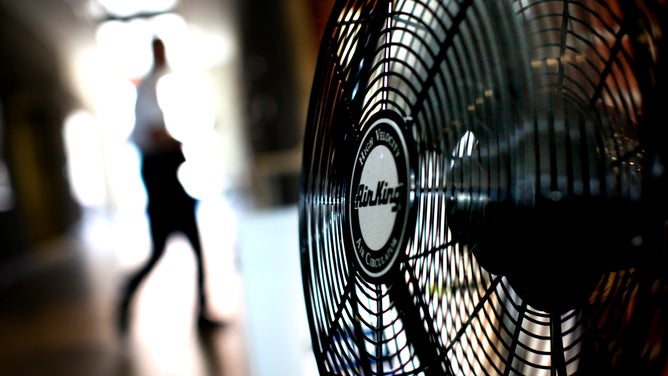 08/09/10:Minneapolis A person walks past an electric fan.