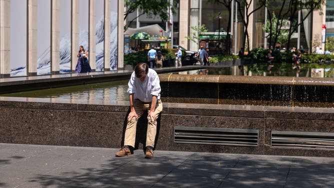 NEW YORK, NEW YORK - JULY 29: A person sits next to a fountain in Manhattan as the region experiences another heatwave on July 29, 2025 in New York City.