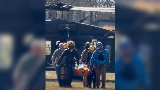 First responders transport an injured hiker to a medical helicopter for transfer to a facility for further treatment.
