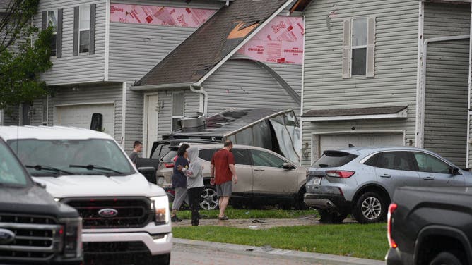 People assess damage to a home in Belton, Missouri, following severe weather on Friday evening.