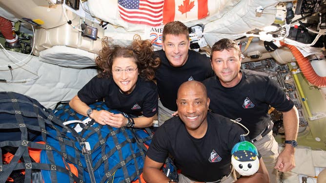 April 7, 2026) – The Artemis II crew – (clockwise from left) Mission Specialist Christina Koch, Mission Specialist Jeremy Hansen, Commander Reid Wiseman, and Pilot Victor Glover – pause for a group photo with their zero gravity indicator "Rise," inside the Orion spacecraft on their way home.