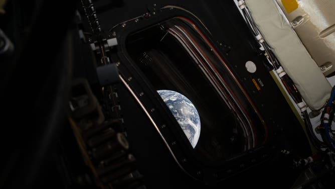 Earth viewed through the window of the Orion spacecraft.