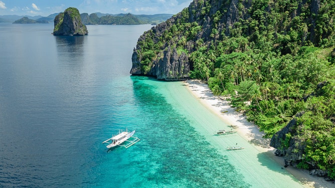 Beautiful Entalula Island Beach Lagoon with typical filipino Balangay Boats. Aerial Drone Point of View. Bacuit Bay, Mimaropa, El Nido, Palawan, Philippines, Asia