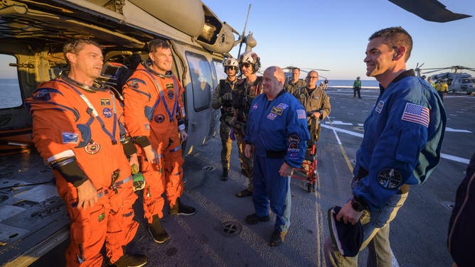 AT SEA - APRIL 10: NASA astronaut Victor Glover, Artemis II pilot, left, and CSA (Canadian Space Agency) astronaut Jeremy Hansen, Artemis II mission specialist, talk with NASA Administrator Jared Isaacman at their Navy MH-60 Seahawk from Helicopter Sea Combat Squadron (HSC) 23 on the flight deck of USS John P. Murtha after they and fellow crewmates NASA Astronauts Victor Glover, and Christina Koch were extracted from their Orion spacecraft after splashdown, Friday, April 10, 2026, in the Pacific Ocean off the coast of California. NASA's Artemis II mission took the quartet on a nearly 10-day journey around the Moon and back to Earth. Following a splashdown at 5:07 p.m. PDT (8:07 p.m. EDT), NASA, U.S. Navy, and U.S. Air Force teams are working to bring the Orion spacecraft aboard