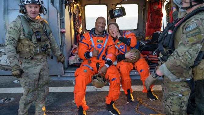NASA astronaut Victor Glover, Artemis II pilot, left, and NASA astronaut Christina Koch, Artemis II mission specialist are seen sitting on a Navy MH-60 Seahawk from Helicopter Sea Combat Squadron (HSC) 23 on the flight deck of USS John P. Murtha after they and fellow crewmates CSA (Canadian Space Agency) astronaut Jeremy Hansen, Artemis II mission specialist, and NASA astronaut Reid Wiseman, Artemis II commander, were extracted from their Orion spacecraft after splashdown, Friday, April 10, 2026, in the Pacific Ocean off the coast of California.