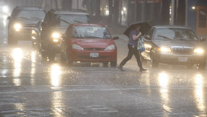 A pedestrian crosses the street as rain falls on downtown Fort Worth, Texas, on Wednesday, June 17, 2015.