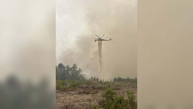 A helicopter drops water on the Pineland Road Fire on April 25, 2026.