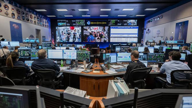 (April 7, 2026) - Members of the International Space Station Expedition 74 (left) and Artemis II (right) crews are seen at once on the screens inside the International Space Station flight control room in Mission Control at NASA's Johnson Space Center in Houston. The two crews connected in a 15-minute ship-to-ship call on April 7, 2026, while the Artemis II crew was on its way back from the Moon.