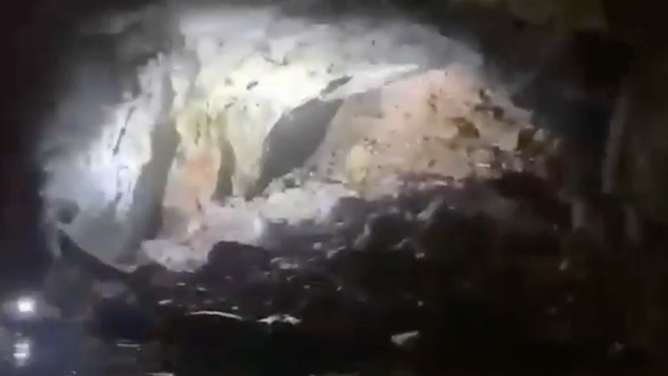 The miner shows rescuers a pile of collapsed rock, telling him how high the water had once been.