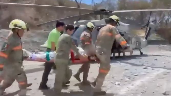 The miner is carried to a medical helicopter for transport to a hospital.