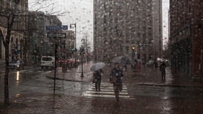 PORTLAND, ME - NOVEMBER 13: Pedestrians on Congress Street in the rain seen through a rain-coated bus stop window on Tuesday, November 13, 2018.