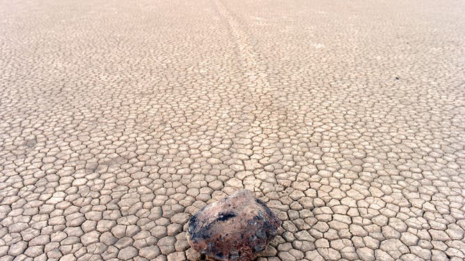 The Racetrack Playa sailing stones are pictured in Death Valley, California, on April 7, 2019. - The Racetrack is a dry lakebed known for its moving rocks that leave trails on the ground. According to the National Park Service webpage the movement of the rocks requires a combination of events: "First, the playa fills with water...As nighttime temperatures plummet, the pond freezes to form sheets of "windowpane" ice...On sunny days, the ice begins to melt and break up into large floating panels, which light winds drive across the playa pool. The ice sheets shove rocks in front of them and the moving stones leave trails in the soft mud bed below the pool surface."