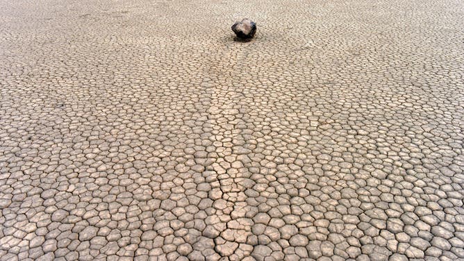 The Racetrack Playa sailing stones are pictured in Death Valley, California, on April 7, 2019. - The Racetrack is a dry lakebed known for its moving rocks that leave trails on the ground. According to the National Park Service webpage the movement of the rocks requires a combination of events: "First, the playa fills with water...As nighttime temperatures plummet, the pond freezes to form sheets of "windowpane" ice...On sunny days, the ice begins to melt and break up into large floating panels, which light winds drive across the playa pool. The ice sheets shove rocks in front of them and the moving stones leave trails in the soft mud bed below the pool surface."