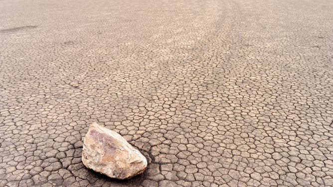 The Racetrack Playa sailing stones are pictured in Death Valley, California, on April 7, 2019. - The Racetrack is a dry lakebed known for its moving rocks that leave trails on the ground. According to the National Park Service webpage the movement of the rocks requires a combination of events: "First, the playa fills with water...As nighttime temperatures plummet, the pond freezes to form sheets of "windowpane" ice...On sunny days, the ice begins to melt and break up into large floating panels, which light winds drive across the playa pool. The ice sheets shove rocks in front of them and the moving stones leave trails in the soft mud bed below the pool surface."