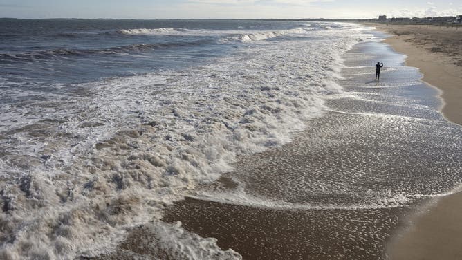 OLD ORCHARD BEACH, ME - SEPTEMBER 24: Renan Perboni, visiting Maine from Brazil, takes a photo of the ocean while standing in the water at a nearly-empty beach in Old Orchard Beach on September 24.