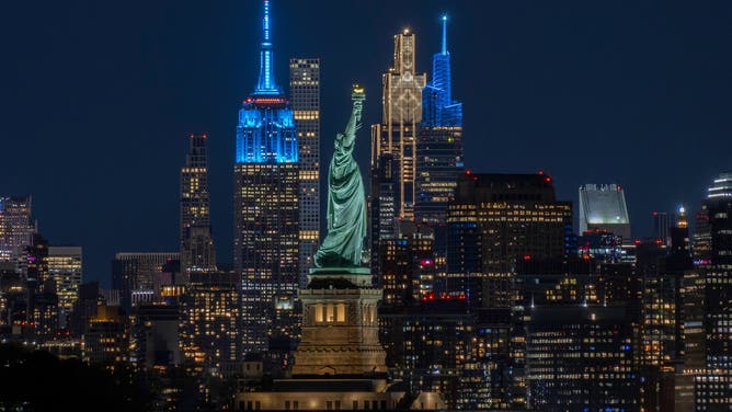 JERSEY CITY, NJ - MAY 2: The Statue of Liberty stands in front of the Empire State Building, 432 Park Avenue, the JPMorgan Chase headquarters, and One Vanderbilt in midtown Manhattan in New York City on May 2, 2026, as seen from Jersey City, New Jersey.