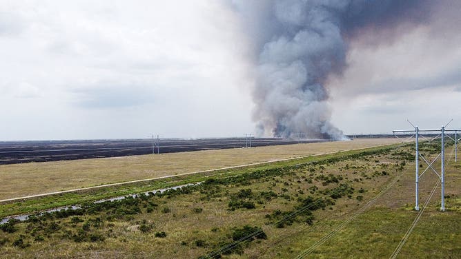 This aerial view shows smoke rising from the Max Road Miramar fire in the Everglades near Pembroke Pines, Florida, on May 11, 2026. The wildfire has scorched nearly 5,700 acres and was about 40 percent contained, according to officials, as the Florida Forest Service continued containment operations with helicopters and emergency crews deployed across the area.