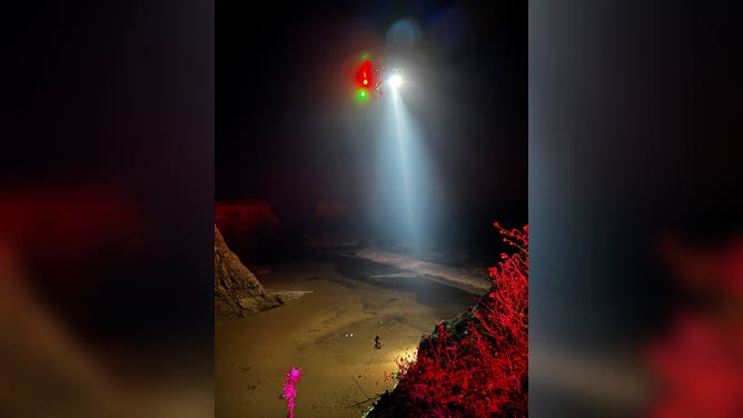 Members of the U.S. Coast Guard prepare to extract individuals who were trapped in a cave at a California beach.