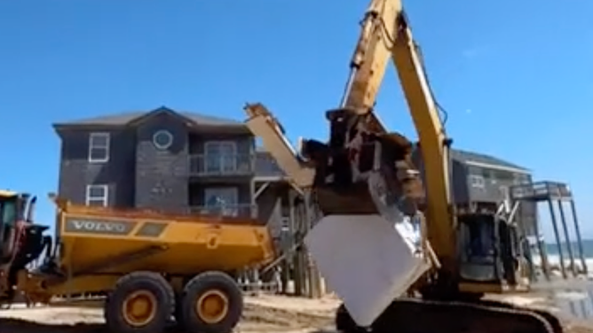 The excavator removing a mattress from the collapsed home.