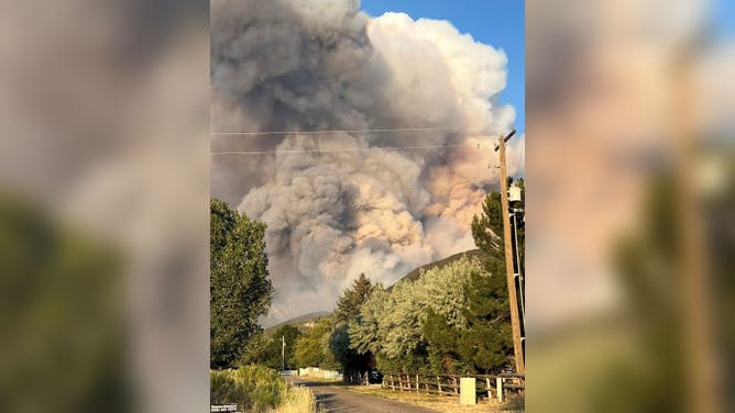 Thick smoke blocks the sky in between mountains in Utah's Beaver County on Tuesday, June 23.