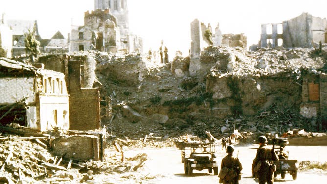 Operation Overlord Normandy, Two American soldiers are watching two United States Army jeeps driving through the ruins of the center of Saint-Lo. August 1944. The town was almost totally destroyed by 2,000 Allied bombers when they attacked German troops stationed there during Operation Overlord in June. France.